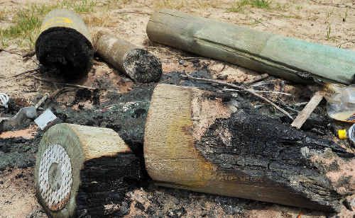 The remains of several large treated timber bollards, burned in the sand dunes along Boambee Beach. The remains of several large treated timber bollards, burned in the sand dunes along Boambee Beach.